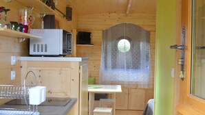 A compact kitchen with wooden cabinets, a microwave, and a small dining area with a table and chair. - Unusual gite equipped to receive up to 5 people (Seux)