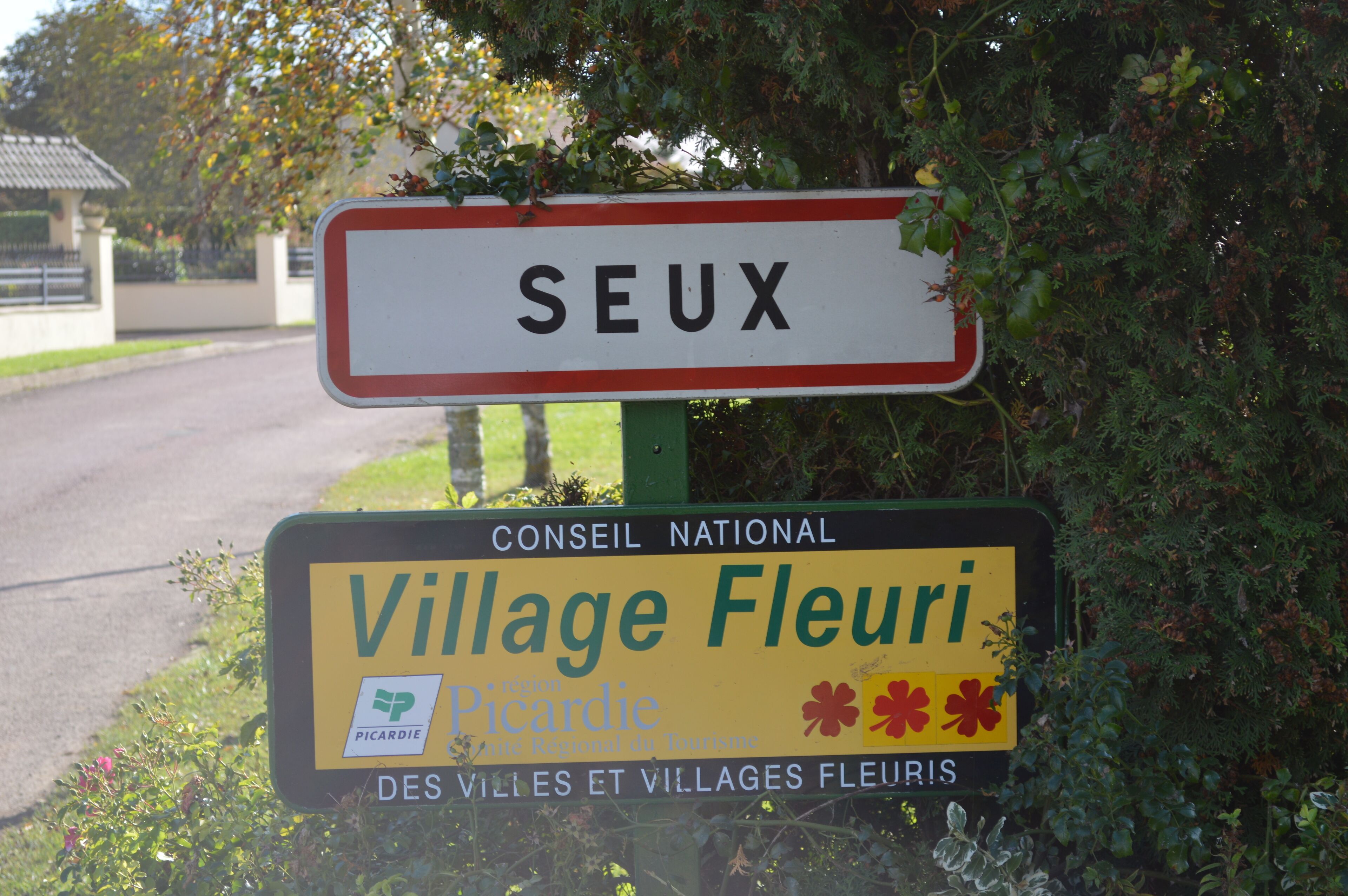 Un panneau pour SEUX et un panneau jaune pour Village Fleuri.