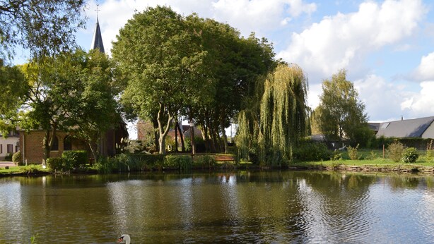 A serene pond with a swan, surrounded by lush greenery and a church spire in the background. - Unusual gite equipped to receive up to 5 people (Seux)