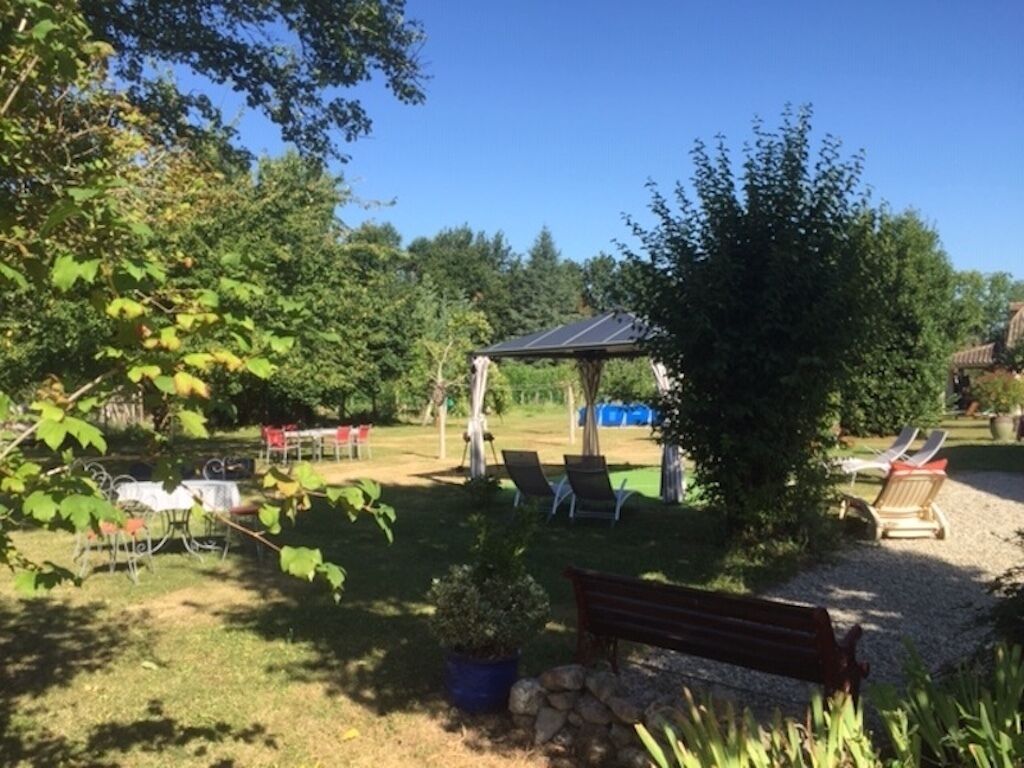 Un espace extérieur aménagé avec une pergola, des chaises longues et un banc.