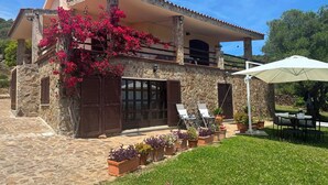 Una casa de piedra con balcón, mobiliario exterior y plantas en macetas.