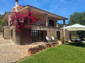 Una casa in pietra con un balcone, posti a sedere all'aperto e piante in vaso.