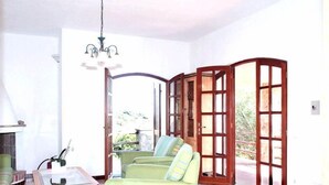 Un salón espacioso con un sofá verde, una mesa de centro de cristal y una araña.