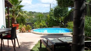 A backyard with a swimming pool, a table with chairs, and a bench. - Charming house in central Algarve in quiet highland, only 18 km to airport (Algarve)