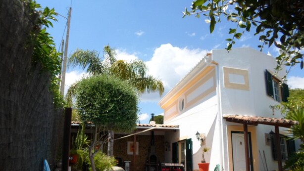A pool surrounded by a patio area with a table and chairs, a covered seating area, and a building with a tiled roof. - Charming house in central Algarve in quiet highland, only 18 km to airport (Algarve)