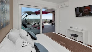 A modern hotel room with a large bed, a TV, and a balcony with outdoor seating. - Top Features! Holiday house with heated pool with sea view, for 10 people (Makarska)