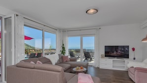 A modern living room with a sectional sofa, a flat-screen TV, and a balcony with a view of the sea. - Top Features! Holiday house with heated pool with sea view, for 10 people (Makarska)