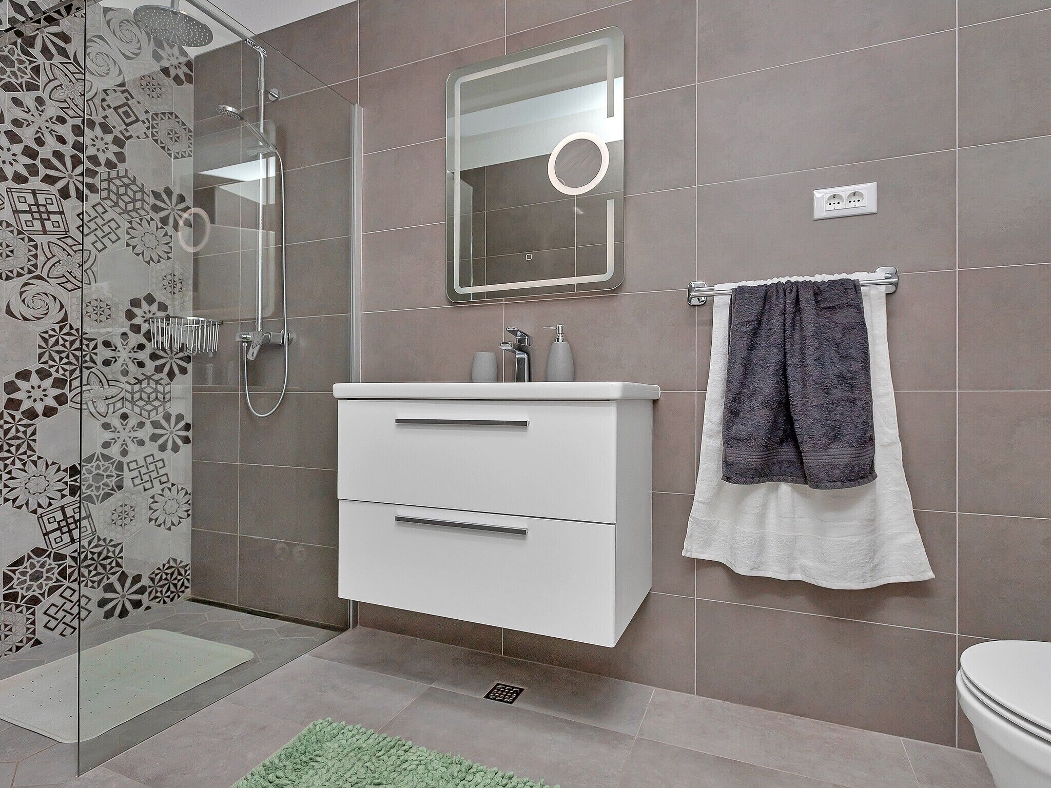 Een moderne badkamer met douche, toilet en wastafel.