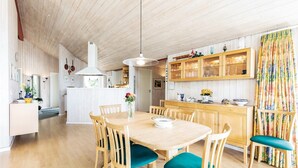 A spacious kitchen with wooden cabinets, a central island, and a dining area with a wooden table and chairs. - 4 bedroom awesome home in Rønne (Rønne)