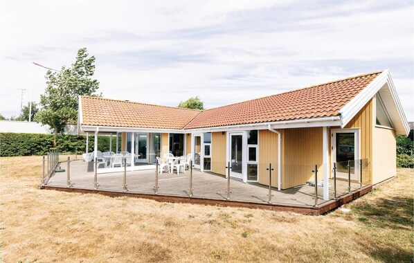A modern house with a covered patio, large windows, and a tiled roof. - 4 bedroom awesome home in Rønne (Rønne)