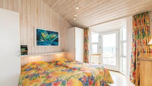 A bedroom with a colorful bedspread, a painting on the wall, and a view of the sea through the window. - 4 bedroom awesome home in Rønne (Rønne)