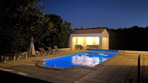 A swimming pool with lounge chairs and a covered seating area.