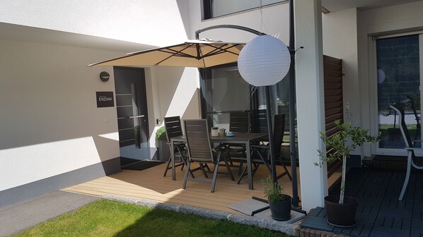 An outdoor patio with a table and chairs, a hanging paper lantern, and potted plants.