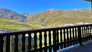 A balcony with a view of a mountainous landscape, including a ski lift and buildings in the valley. - Cozy apartment at the foot of the slopes, pets allowed (Les Menuires)