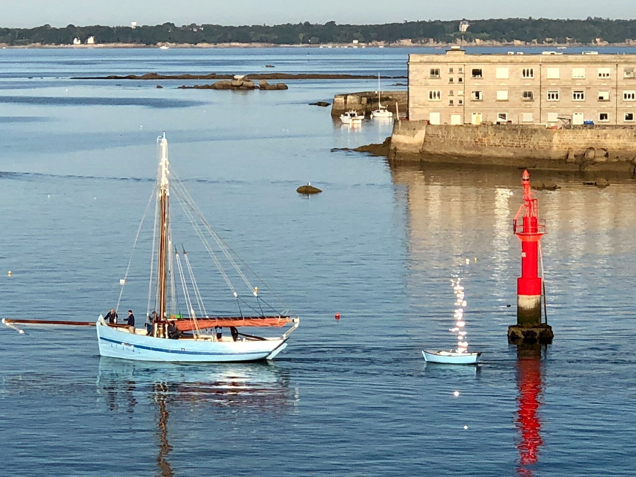 A harbor with a sailboat and a red lighthouse.