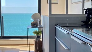 Une cuisine moderne avec vue sur la mer, une petite table agrémentée d’objets décoratifs et une grande fenêtre.
