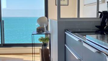 Une cuisine moderne avec vue sur la mer, une petite table agrémentée d’objets décoratifs et une grande fenêtre.