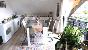 A modern kitchen with a dining area, white cabinetry, and a view of the outside. - Apartment with balcony in a quiet, sunny location on the outskirts of Saxon Switzerland (Sebnitz)