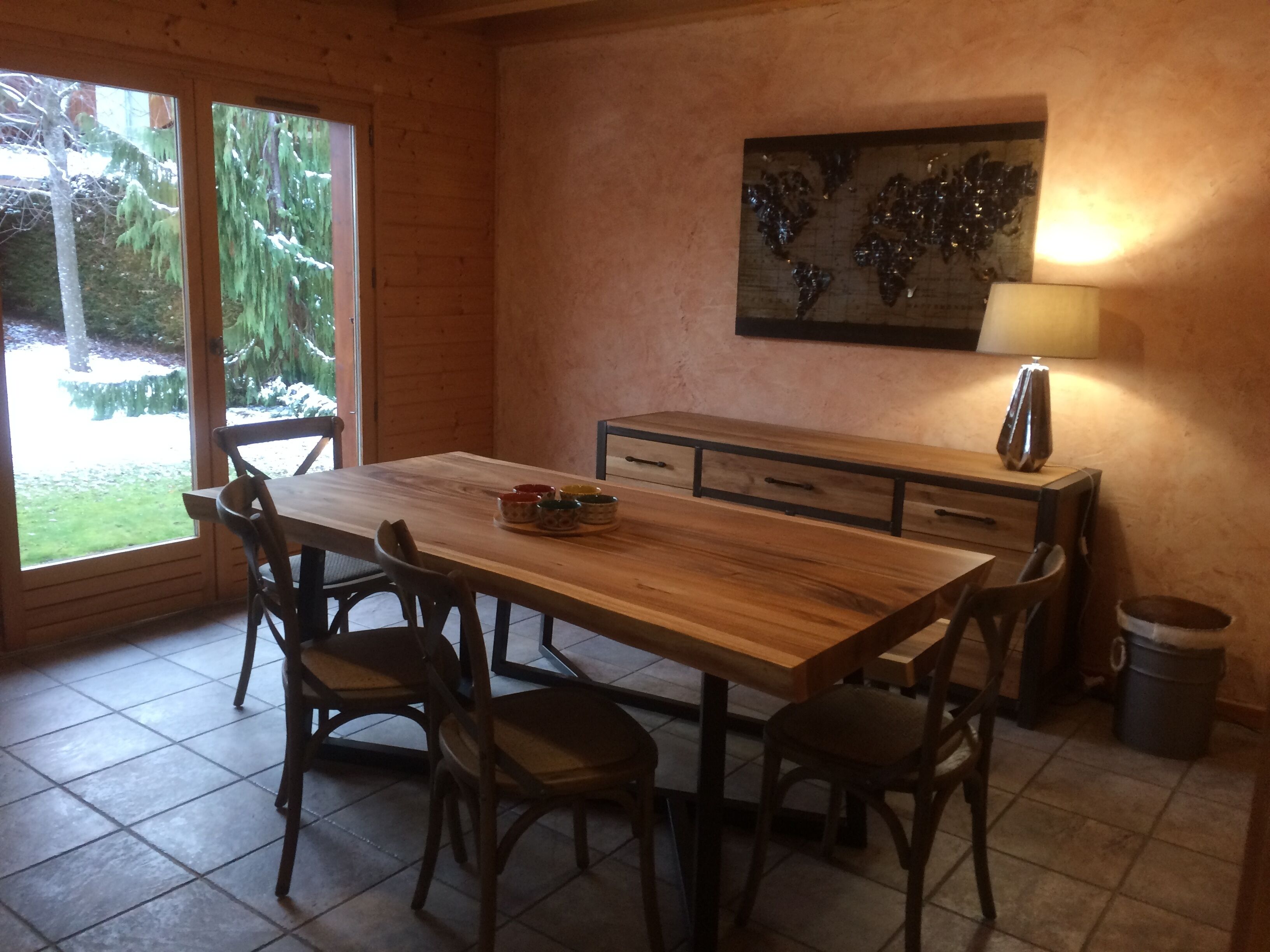 Une table de salle à manger en bois, des chaises, un petit meuble et un tableau accroché au mur.