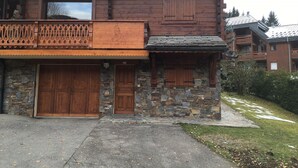 Ein Holzhaus mit Steinmauern, zwei Holztüren und einem Balkon mit Geländer.
