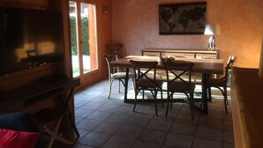 Ein Essbereich mit einem Holztisch, Stühlen, einem Fernseher und einer Weltkarte an der Wand.