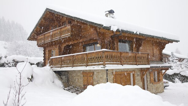 Eine Holzhütte mit Balkon, umgeben von Schnee.