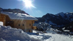 A wooden chalet with a snow-covered roof, situated in a snowy mountainous area with clear skies. - Upscale chalet not far from the ski slopes  (Châtel)