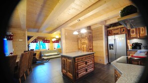 A wooden interior with a kitchen area, wooden cabinets, a refrigerator, and a dining area with chairs and a table. - Upscale chalet not far from the ski slopes  (Châtel)