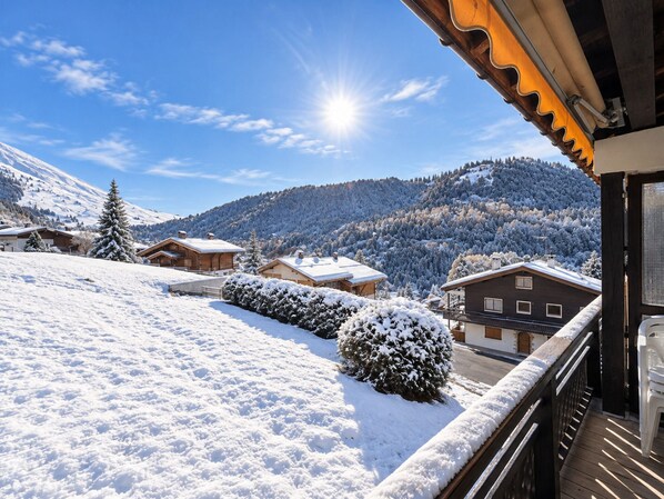 A snow-covered mountain landscape with wooden houses and a balcony overlooking the scenery.