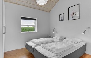 Ein Schlafzimmer mit einem Bett, zwei Nachttischen, einem Fenster und zwei Wandlampen.