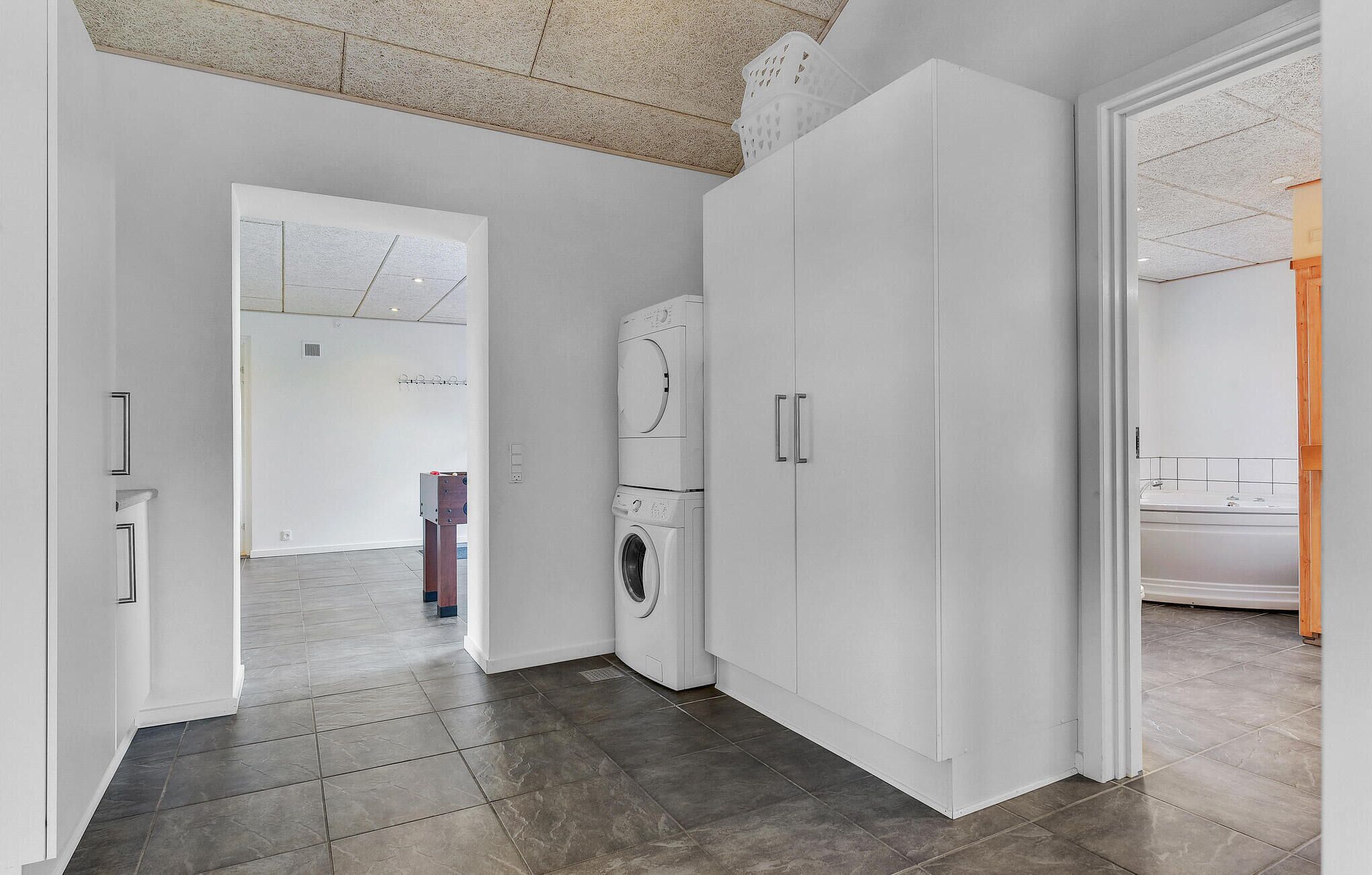 Un appartement moderne doté d’un espace buanderie, d’une porte donnant sur une autre pièce et d’un sol carrelé.