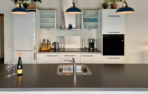 A modern kitchen with white cabinets, a stainless steel sink, and blue pendant lights. - Stunning home in Sydals with sauna (Sydals)