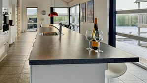 Una cocina moderna con una isla grande, un comedor y vistas al exterior.