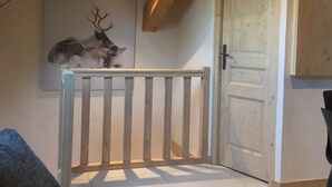 Um quarto com teto de madeira, porta branca e um chifre de veado decorativo na parede.