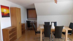 A dining area with a wooden table, black chairs, and a wooden cabinet. - quiet, attractive apartment with 2 bedrooms (Meiningen OT Walldorf)