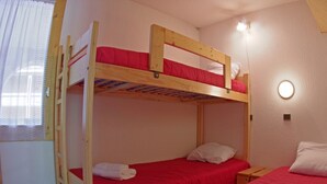 Een slaapkamer met een stapelbed, een ladder en een klein nachtkastje.