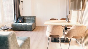 Una sala de estar moderna con un sofá, una mesa de comedor con sillas y un televisor montado en la pared.