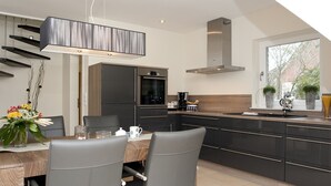 A modern kitchen with dark cabinetry, a built-in oven, and a window with a view of greenery.