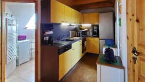 Eine kompakte Küche mit Holzbalken, einem Spülbecken, einer Mikrowelle und einem kleinen Kühlschrank.