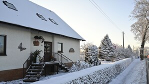 Ein Gebäude mit verschneitem Dach, einer Treppe, die zum Eingang führt, und einem verschneiten Weg.
