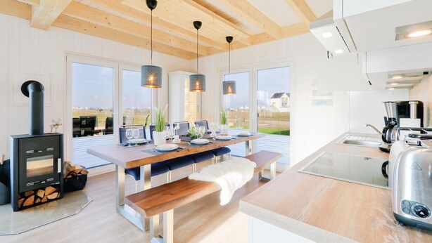 Une cuisine moderne dotée d’un grand îlot central, d’une cuisinière intégrée et de grandes fenêtres offrant une vue sur l’extérieur.
