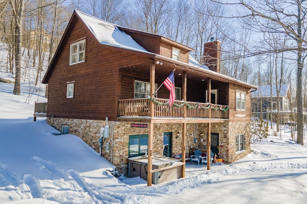 A wooden cabin with a stone foundation, a balcony, and an American flag.