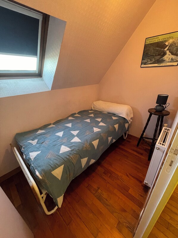 A small, single-bed room with a sloped ceiling, a window, a radiator, and a poster on the wall. - country house with free wifi in a quiet area 45 mins from mont st michel (Saint-Laurent-De-Cuves)