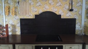 Una cucina con un piano di lavoro in legno scuro, un fornello e una rastrelliera a parete con utensili da cucina.