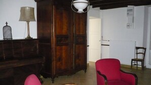 Una stanza con un armadio in legno, due sedie rosse, un tavolo e una lampada.