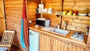 A compact kitchen with wooden walls, a sink, a stove, and a small refrigerator.