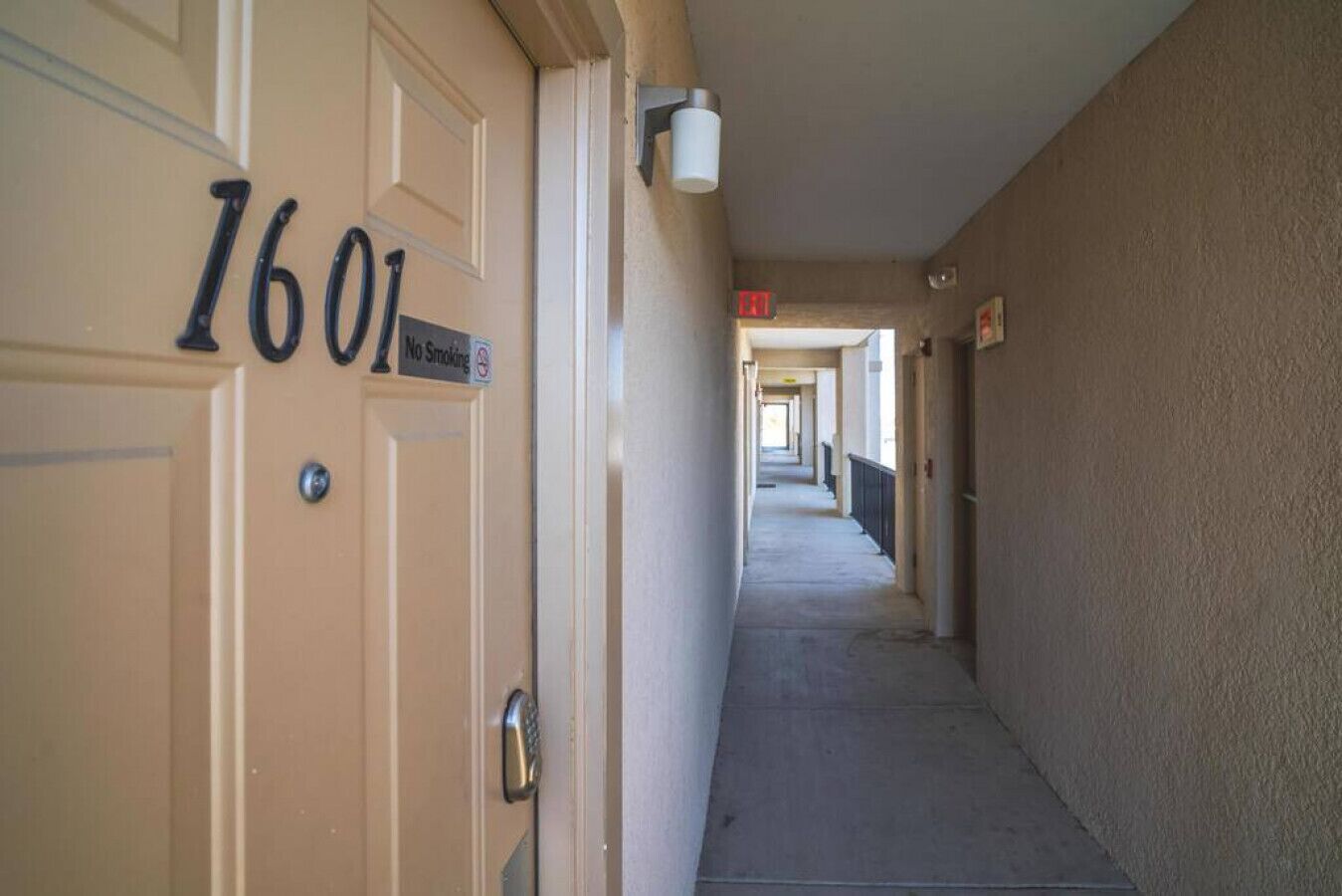A hallway with doors numbered 1601, a no smoking sign, and a light fixture on the wall.