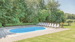 A swimming pool with a tiled deck, surrounded by a grassy area and a row of white lounge chairs. - Nice apartment in Simpelveld with swimming pool (Simpelveld)