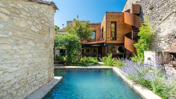 Une piscine entourée de murs de pierre et de bâtiments en bois dotés de balcons.