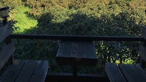 A view from a wooden deck overlooking a coastal landscape with a red-roofed building and the ocean in the distance. - Light-flooded country house with WiFi connection * Last minute offer * (La Orotava)